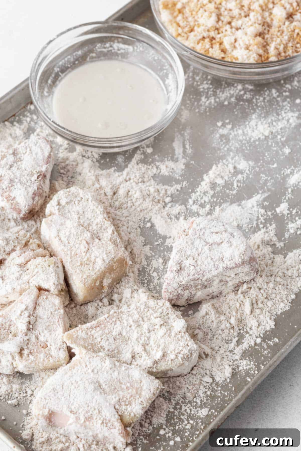 Pieces of young green jackfruit thoroughly covered in a light dusting of oat flour, ready for the next step in the breading process.