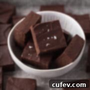 Closeup shot of cubes of dairy-free fudge in a white bowl and garnished with some flaky sea salt.