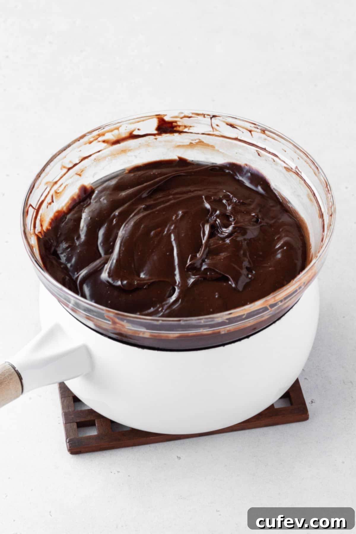 Fudge ingredients in a bowl on top of a double boiler after melting and being mixed.