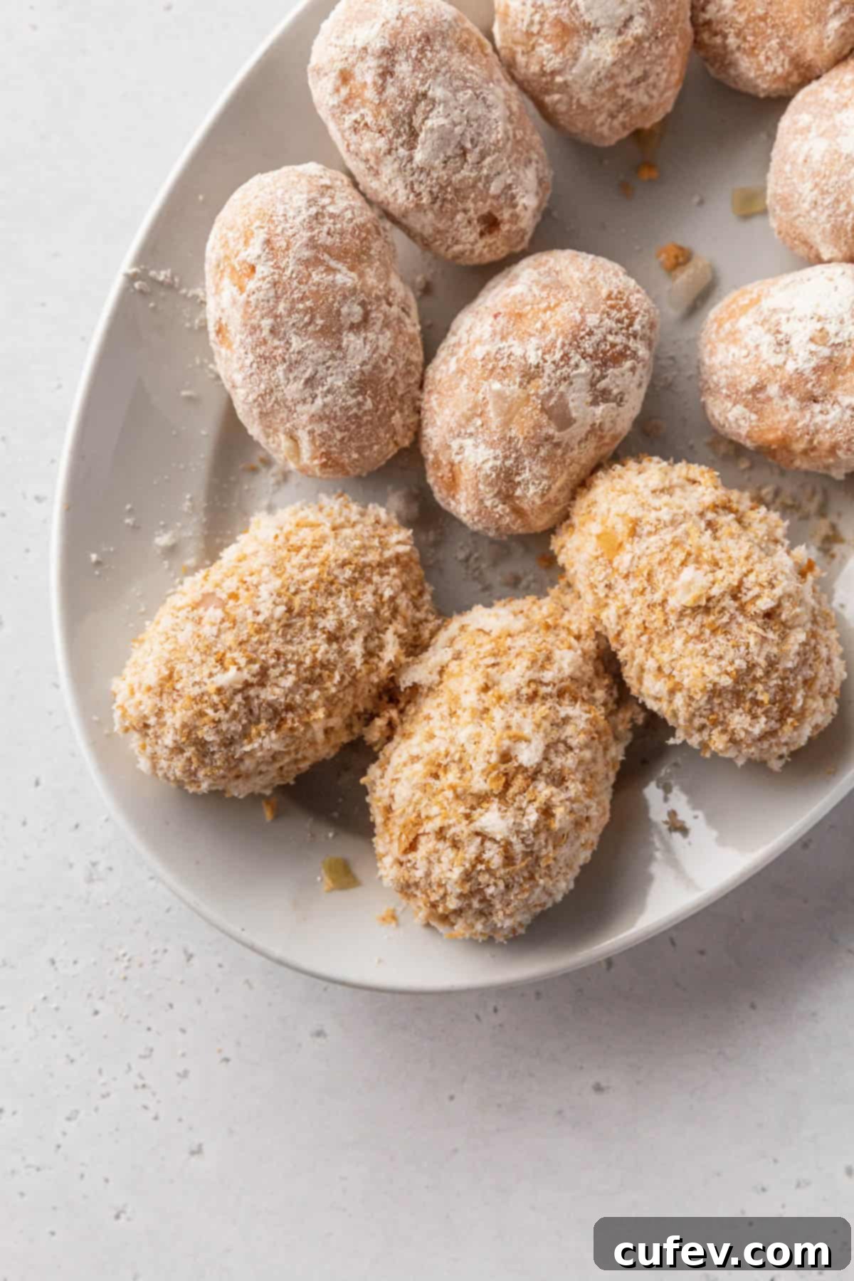 Assembled vegan potato croquettes on a plate showing the various stages of the standard breading procedure.