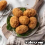 Vegan curry potato croquettes on a serving platter atop a wooden cutting board.