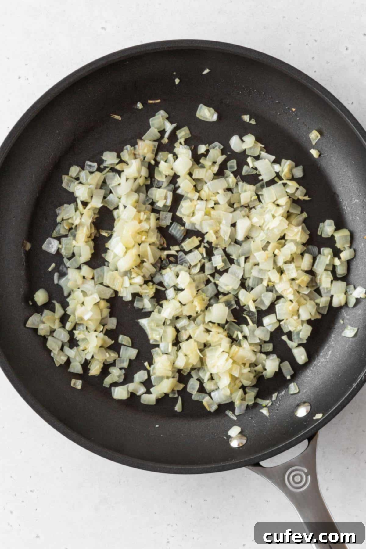Sautéed diced onions in a pan.
