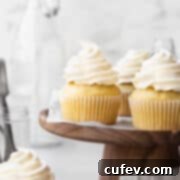 Guilt-Free Cupcakes 12 Square hero shot of a dairy free vanilla cupcakes on a wooden cake stand.