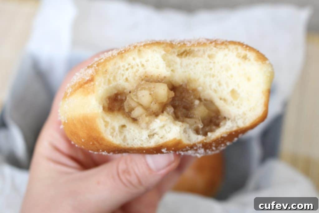 Apple doughnut being filled with apple compote from a piping bag