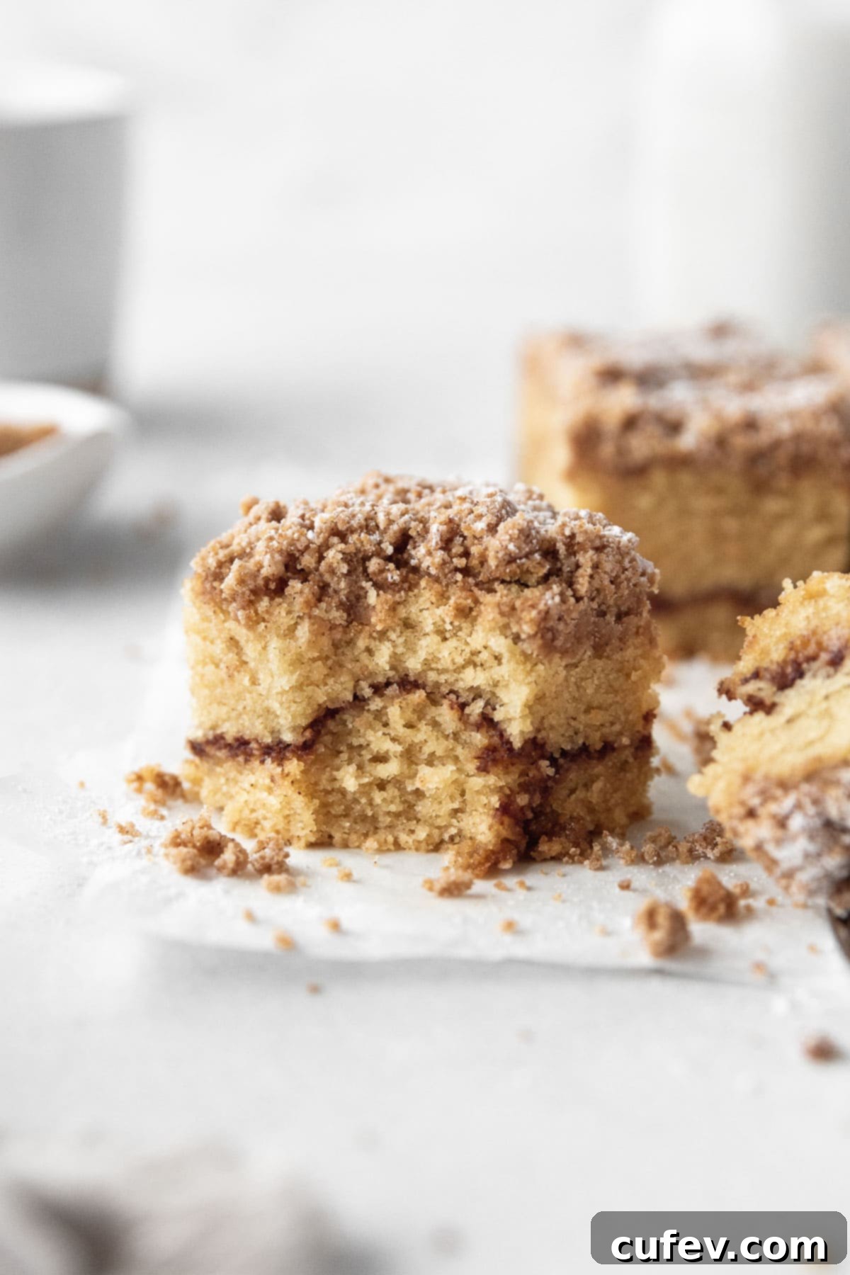 A square of gluten-free coffee cake with a bite taken out, showcasing the moist crumb and generous cinnamon topping.