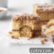 Square hero shot of a square of gluten-free coffee cake with a bite taken out, showing the tender interior and crumb topping.