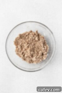Gluten-free crumb cake topping ingredients mixed in a glass bowl, appearing as coarse, buttery crumbs.