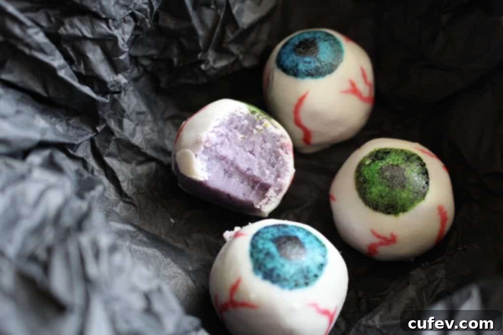 Close-up of a finished Halloween white chocolate eyeball, revealing intricate gel food coloring details and the purple sweet potato filling