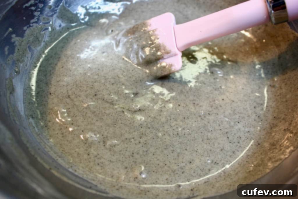 A bowl filled with dark, rich black sesame cupcake batter, ready to be poured into liners.