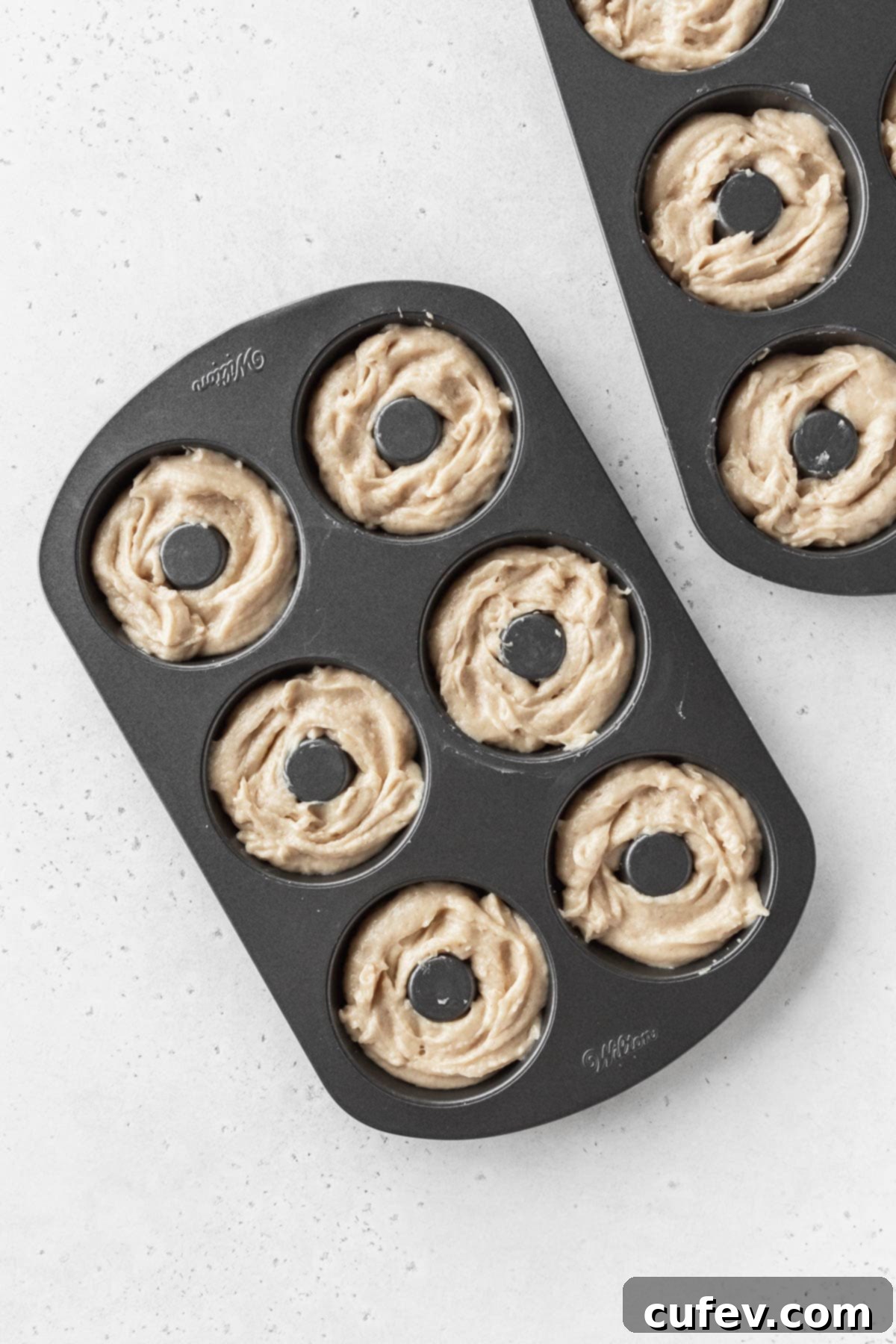 Overhead shot of unbaked dairy-free donut batter in two donut pans.