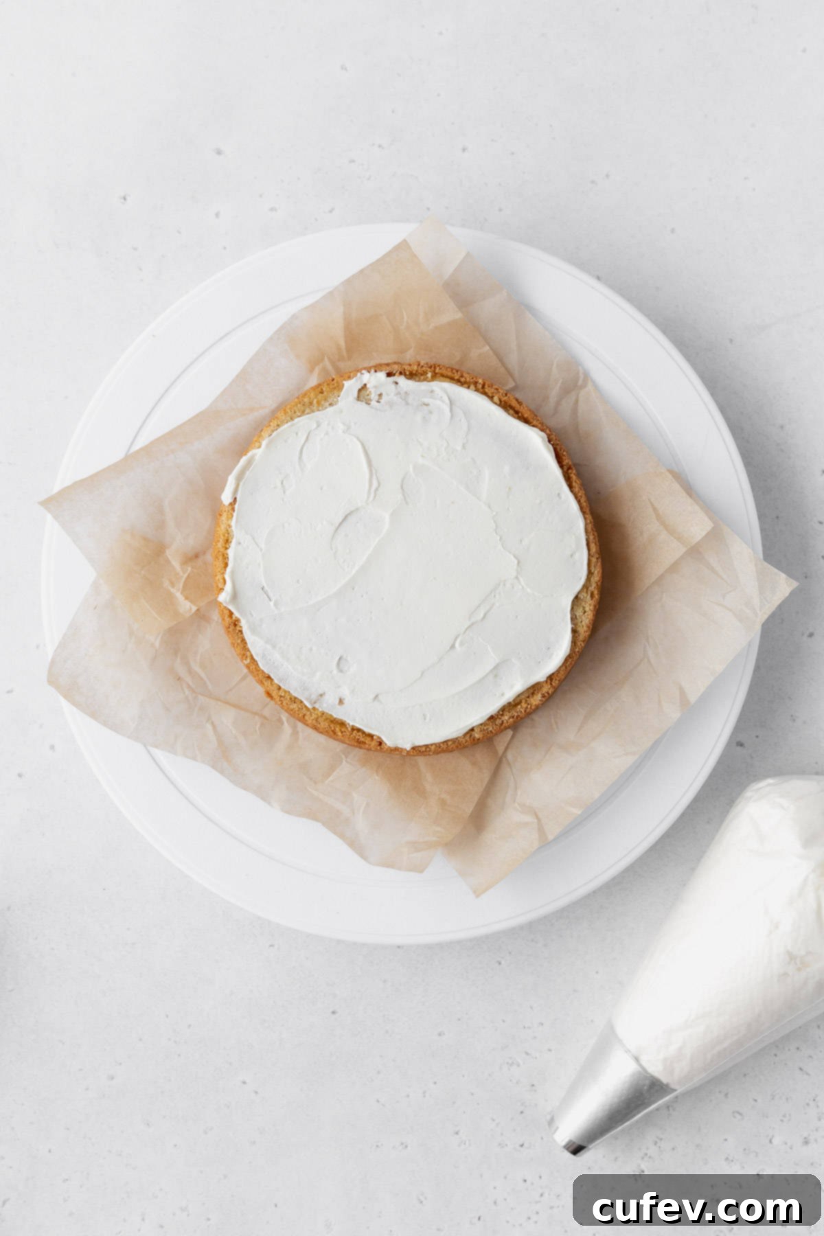 Adding a layer of buttercream on top of the first cake layer.
