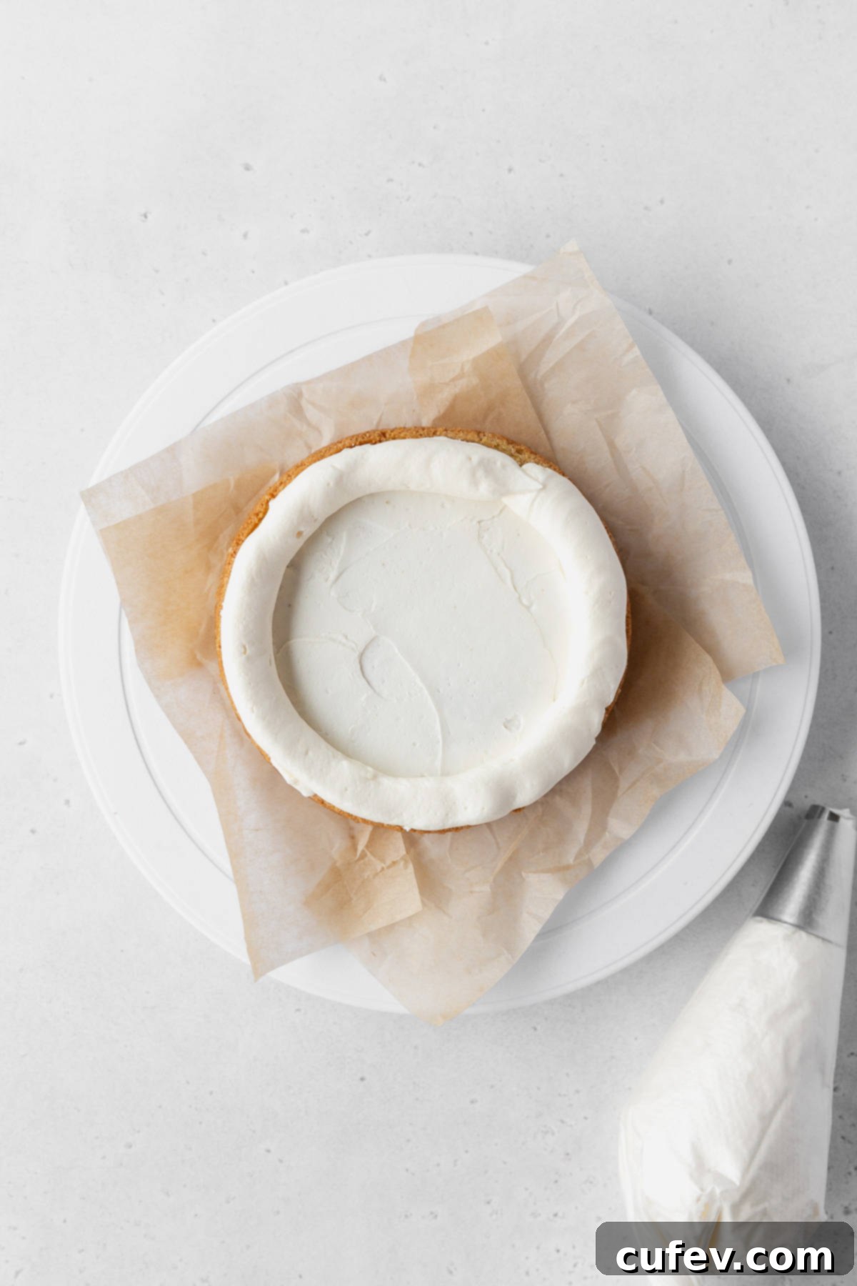 Piping a thick layer of lemon buttercream around the edge of the cake layer.