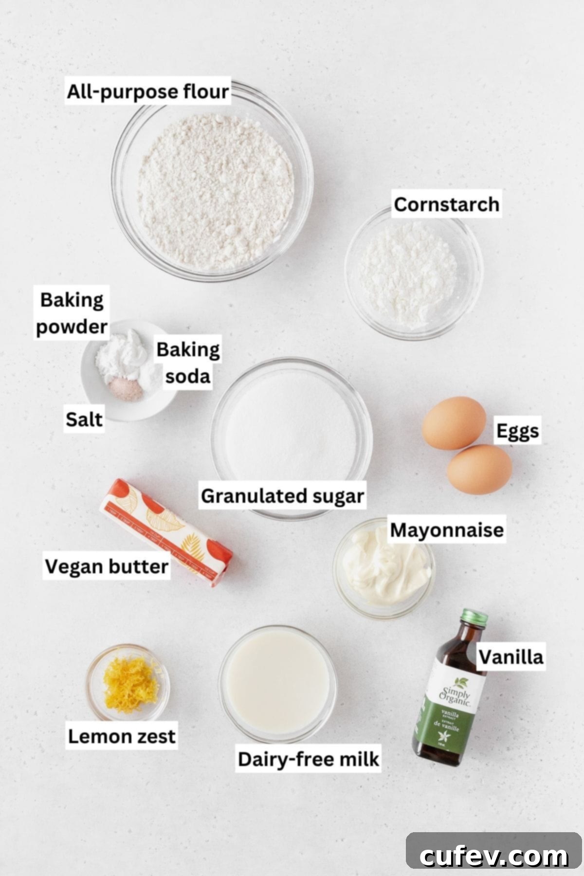 Ingredients needed for making lemon curd cake recipe on a white table with text overlay.