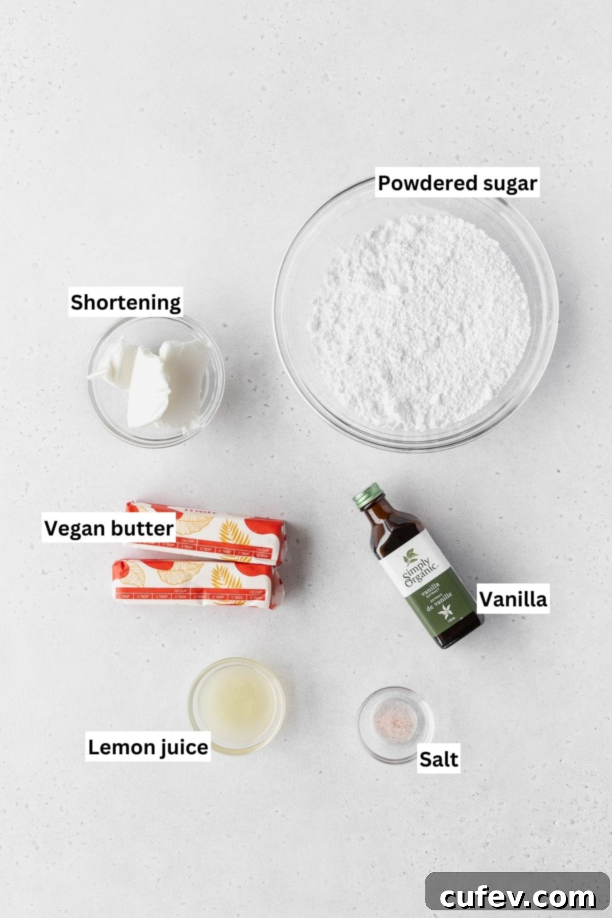 Ingredients for making lemon buttercream frosting on a white table with text overlay.