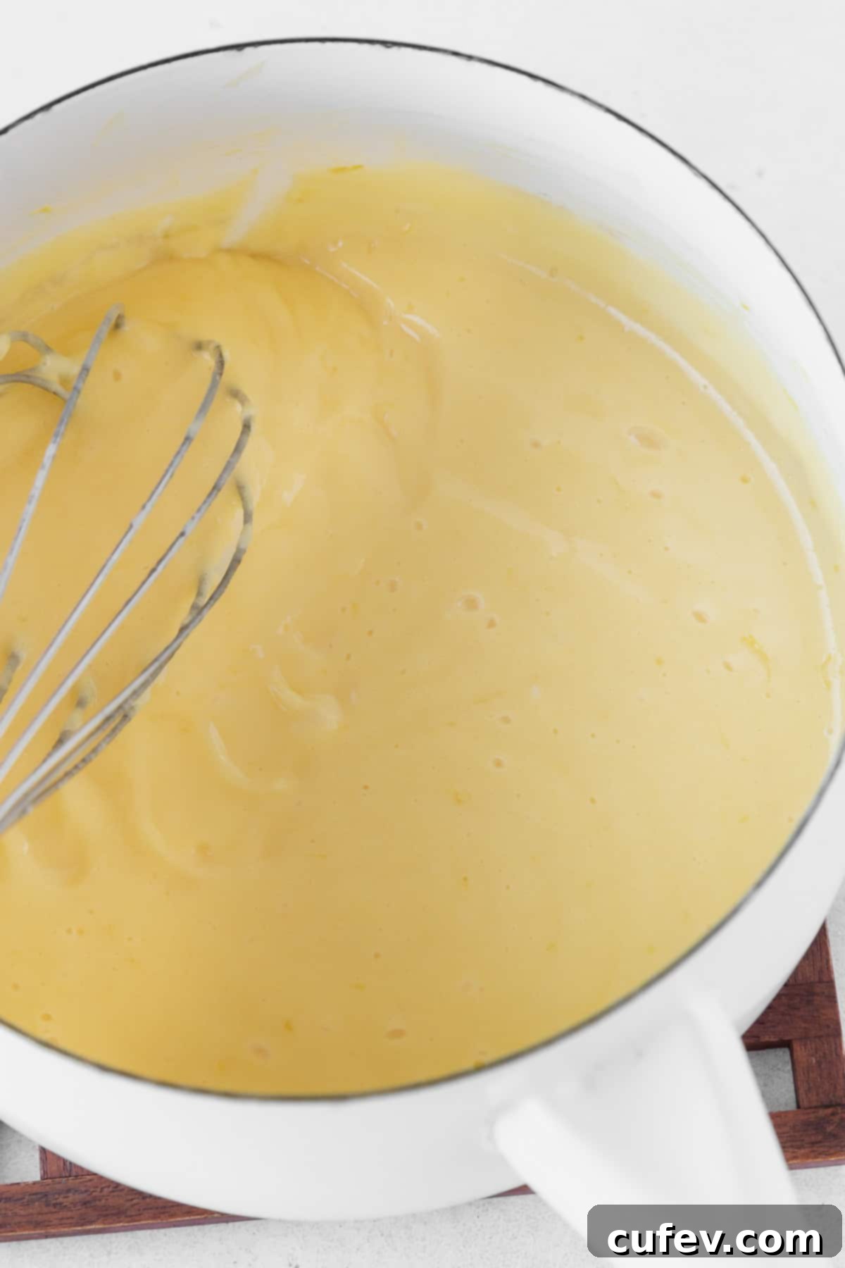 Cooking the dairy-free lemon curd in a white saucepan.