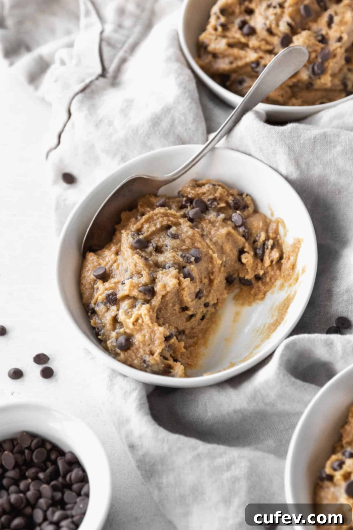 45 degree angle shot of a half-eaten bowl of dairy-free gluten-free edible cookie dough with a spoon.