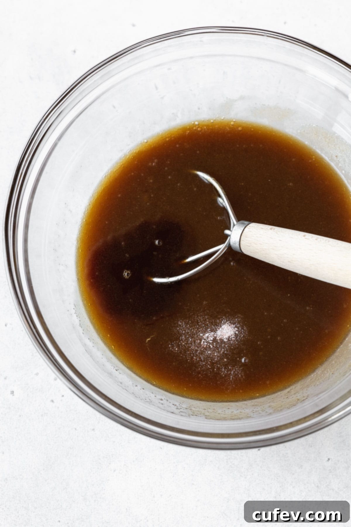 Butter and sugar after whisking together with a danish dough whisk, showing a smooth mixture.