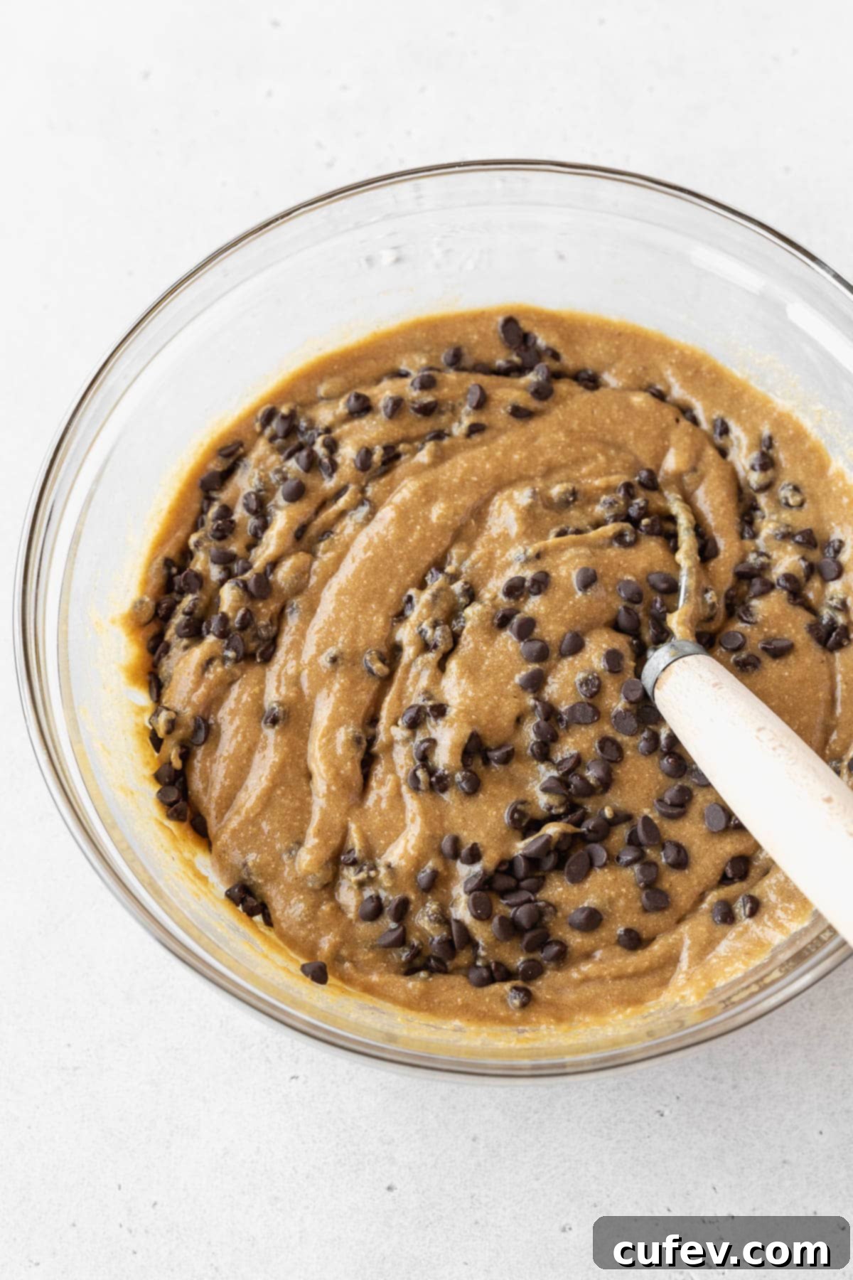 Step 3 for making gluten-free edible cookie dough — whisking in mini chocolate chips into the dough.