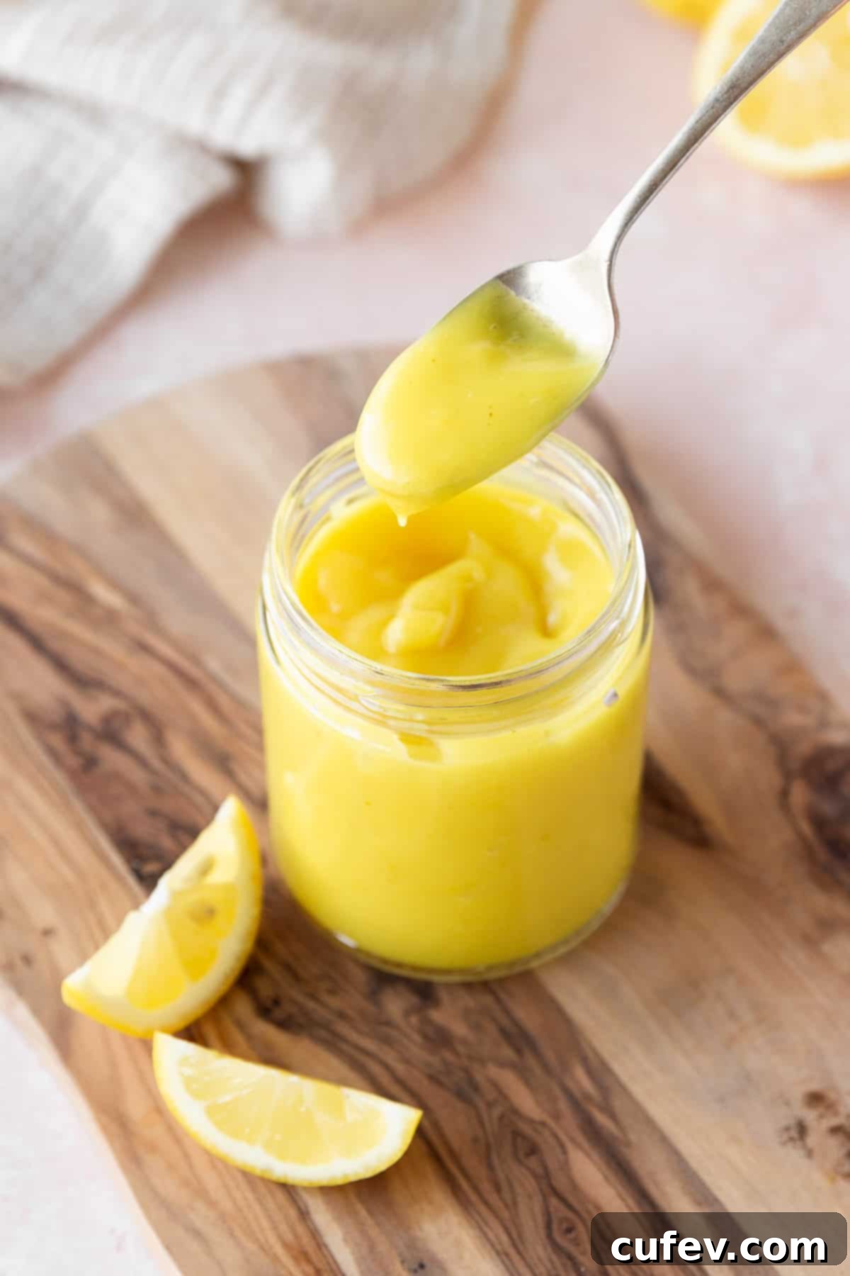 Velvety Vegan Lemon Curd 3 45 degree angle shot of a spoonful of vegan lemon curd above the mason jar to show the thick consistency of the spread.