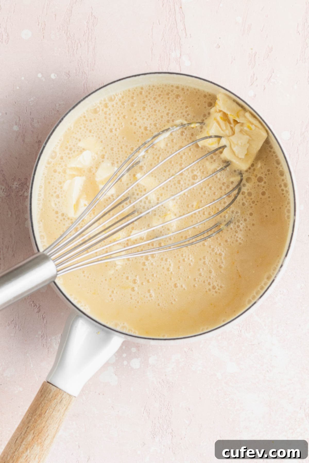 Velvety Vegan Lemon Curd 7 Whisking the butter into the warmed vegan lemon curd mixture in a saucepan on the stove, demonstrating the cooking process.