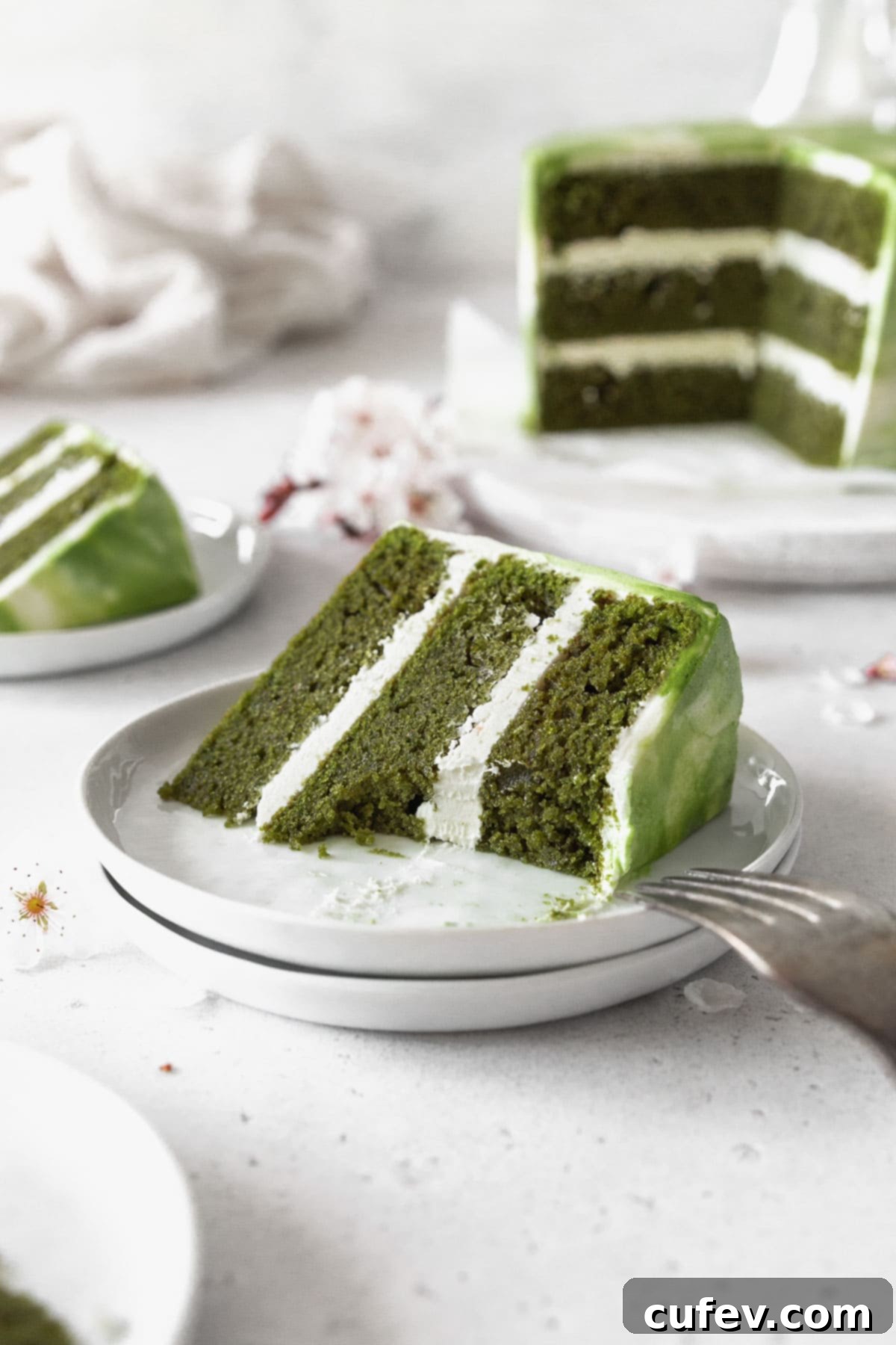 An up-close shot of a piece of matcha cake on a dessert plate with a bite taken out of it. 