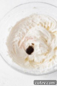 Buttercream frosting with salt and vanilla paste in a glass bowl.
