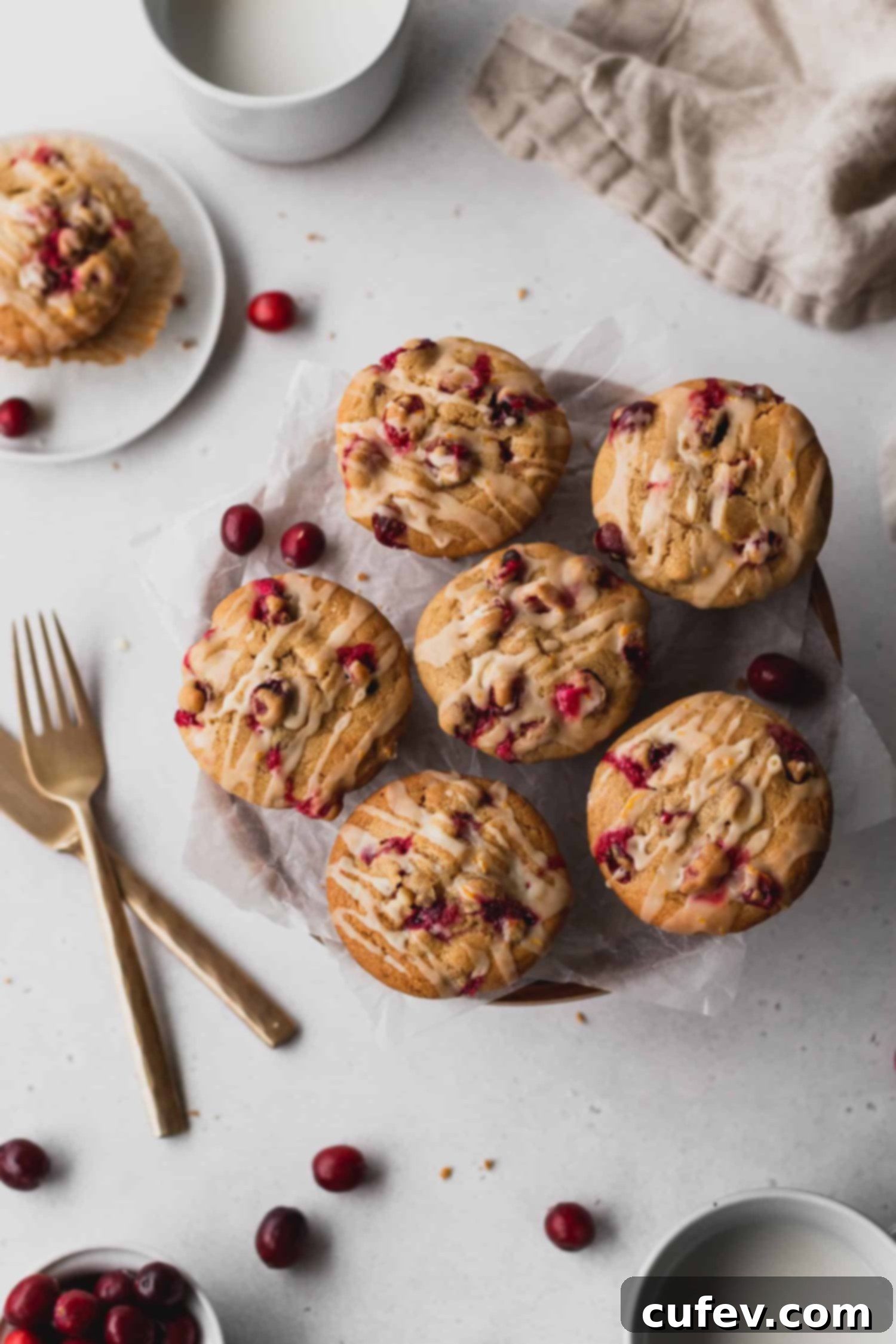Close-up of cranberry orange muffins with a delicate orange icing drizzle, ready to be served.