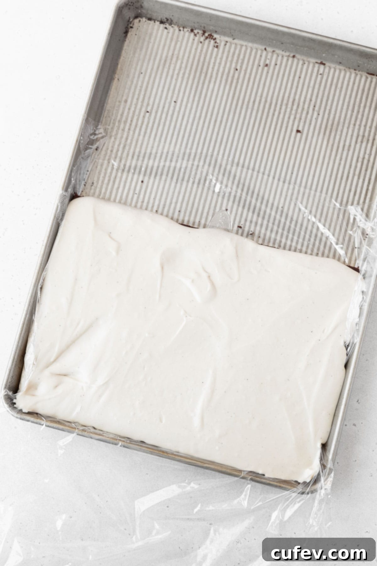 The creamy dairy-free ice cream being smoothly spread onto the bottom half of a gluten-free ice cream sandwich cookie layer, forming the delicious filling.