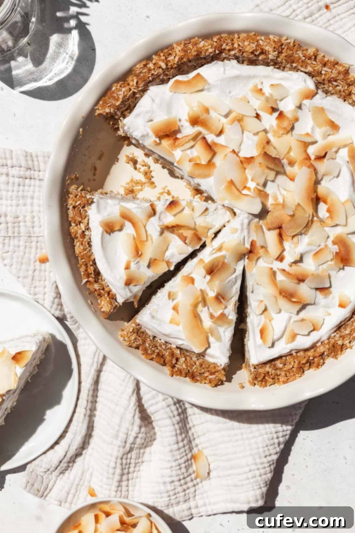 Overhead shot of vegan gluten-free coconut cream pie in a pie dish with two slices prepped to serve.