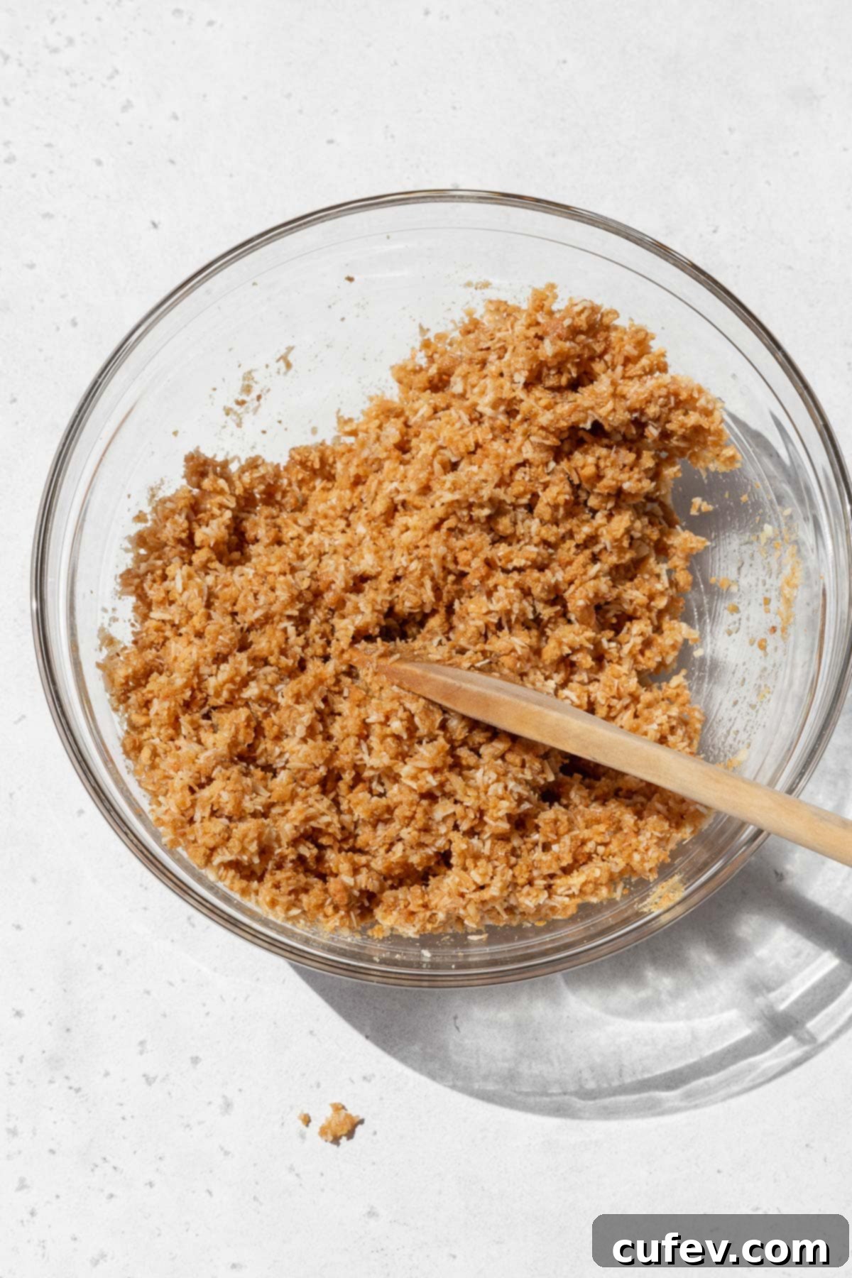 Gluten-free coconut pie crust mixture in a bowl after adding the vegan butter. It looks like wet sand.