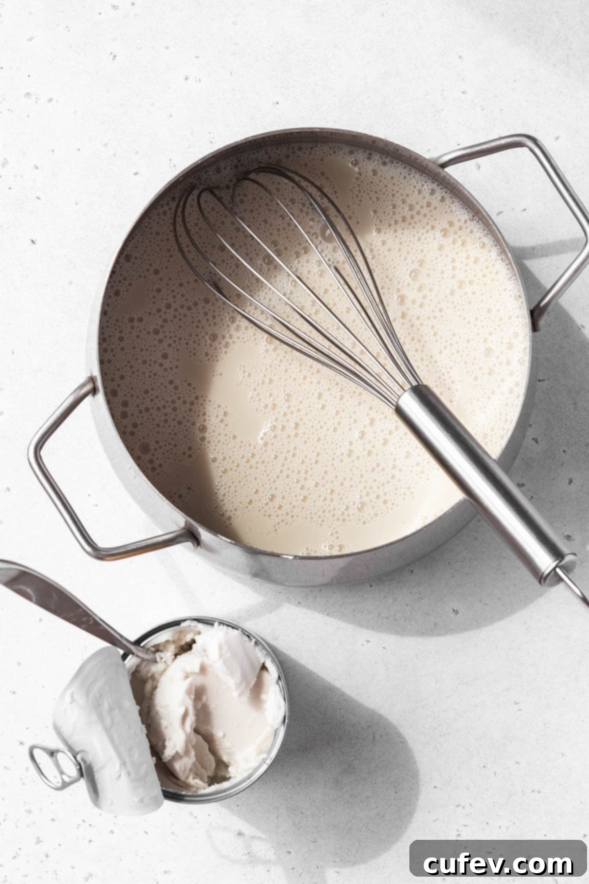 Wet ingredients added to the saucepan for making vegan coconut pudding next to an open can of coconut cream.