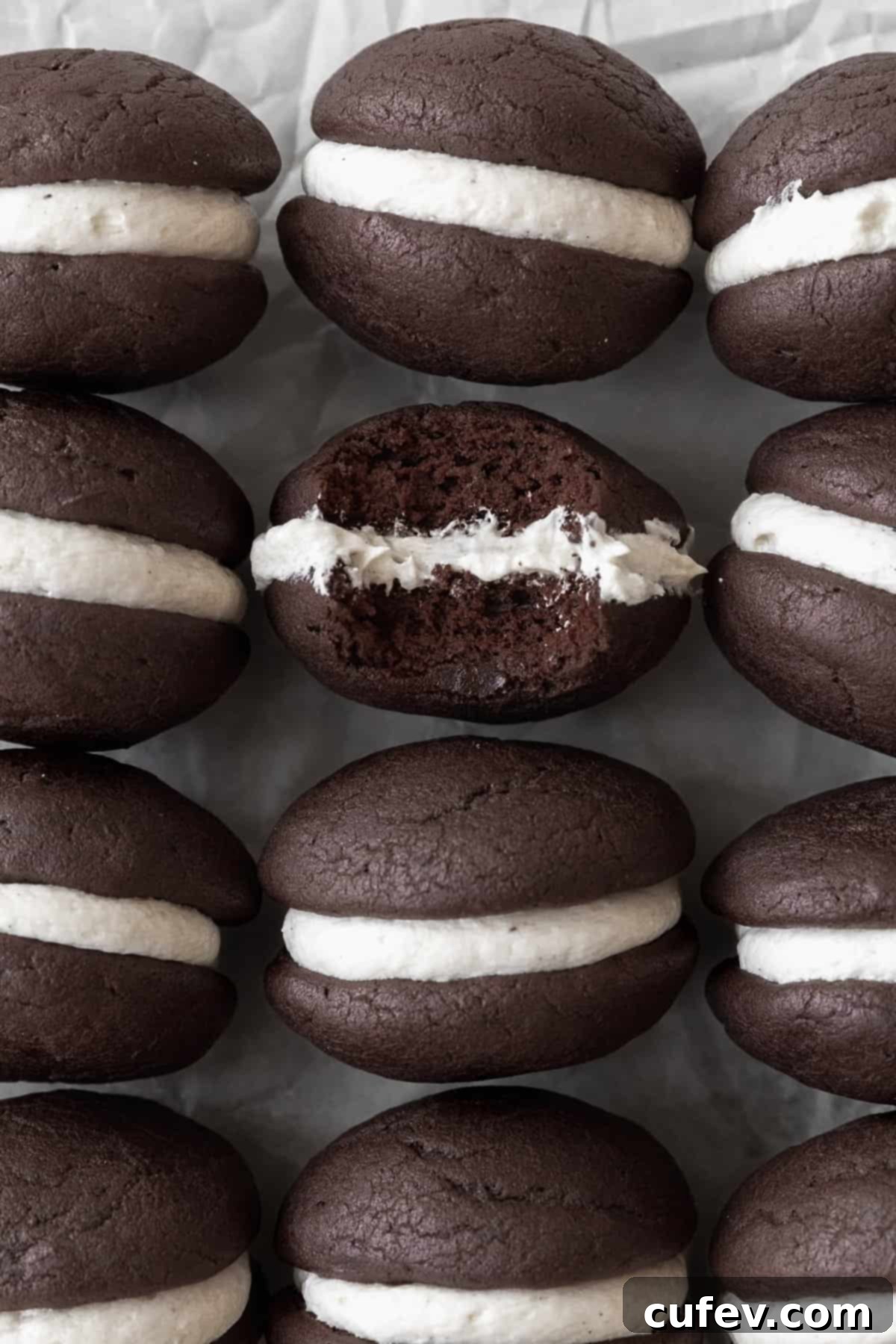 Gluten Free Whoopie Pies 2 Gluten-free whoopie pies on a white sheet of parchment paper. One of the cookies has a bite taken out of it.