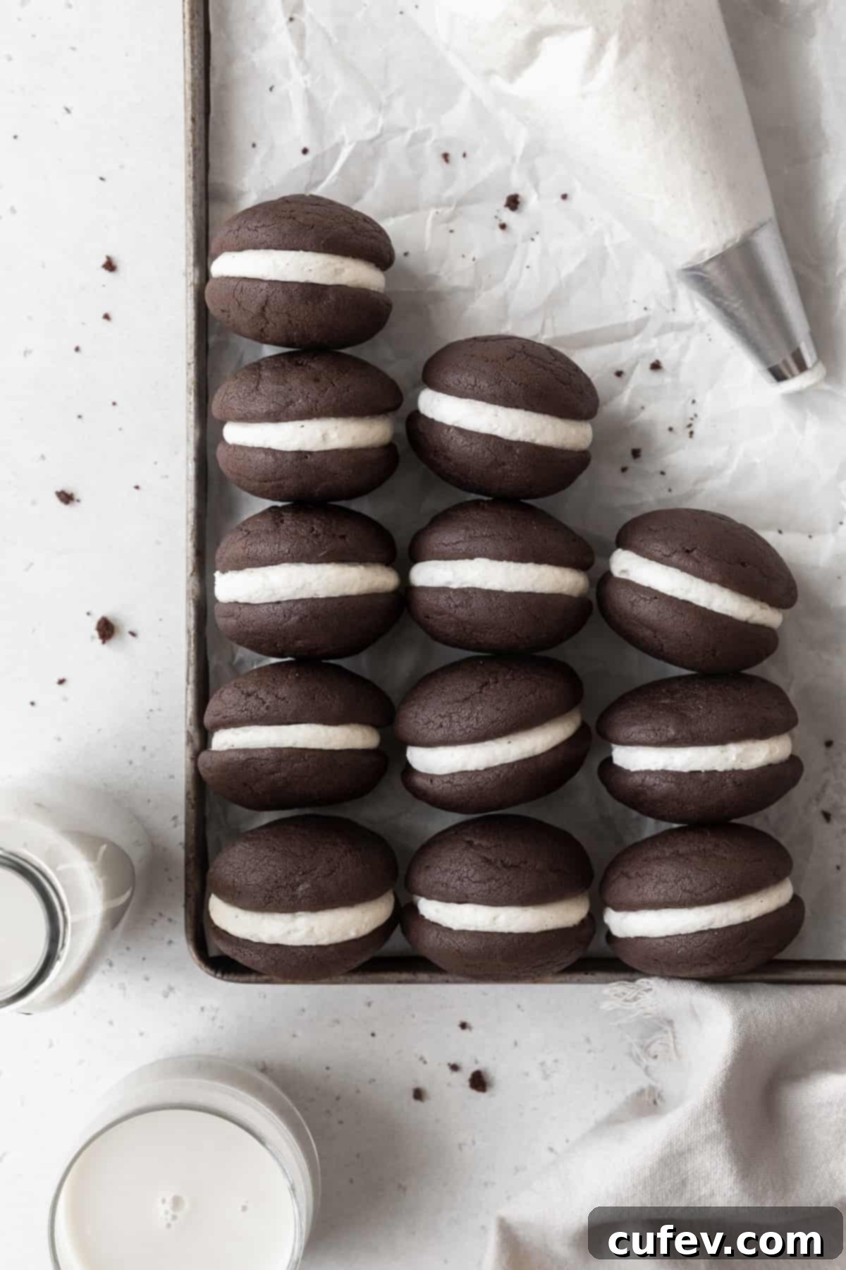 Gluten Free Whoopie Pies 3 A parchment paper lined baking tray with gluten-free whoopie pies and a piping bag.