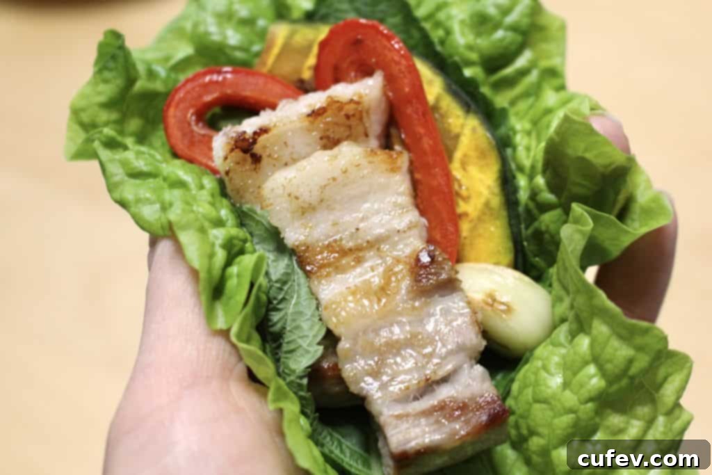 Close-up of grilled pork belly pieces being dipped into a small bowl of sesame oil and salt