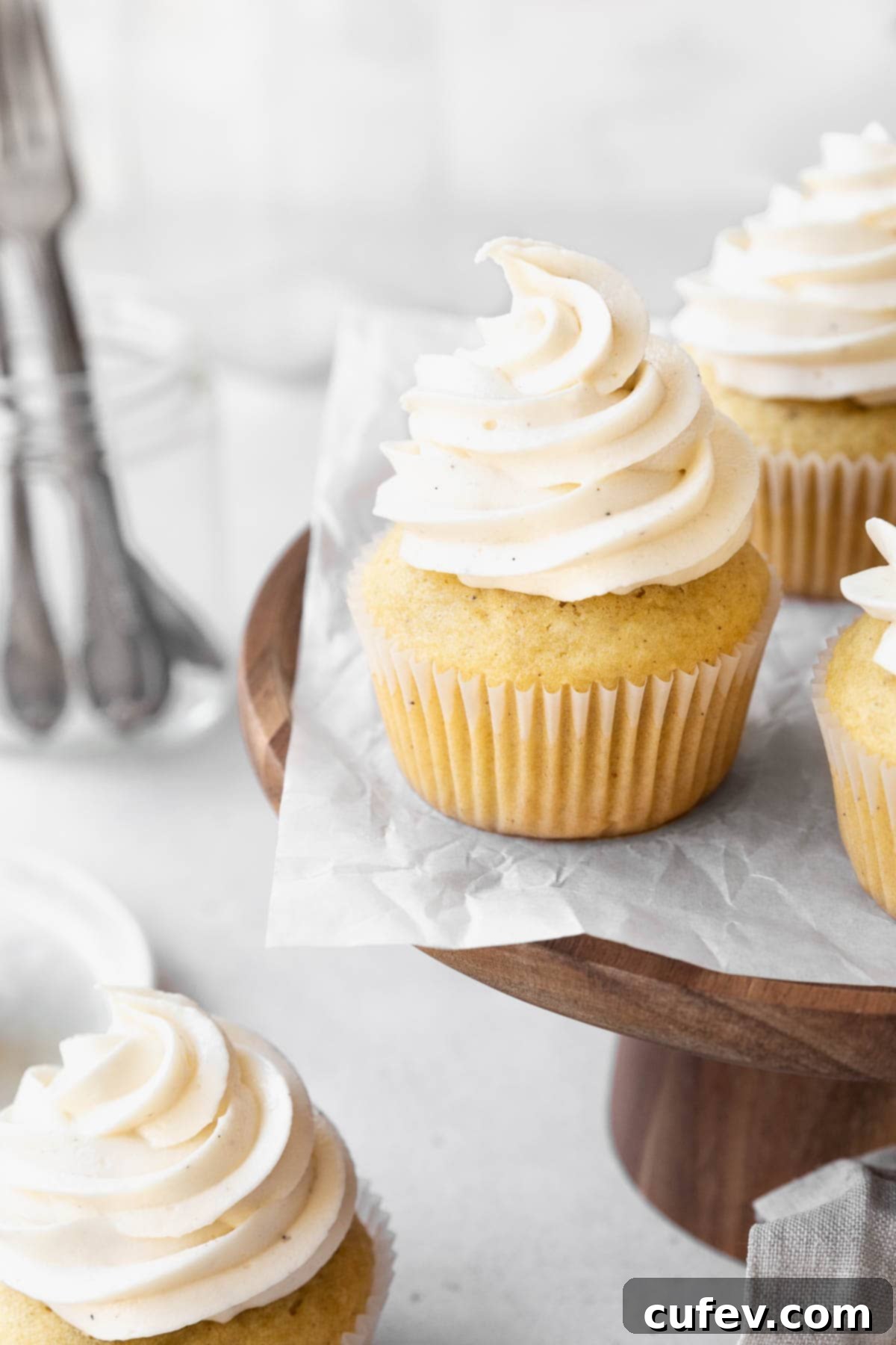 Wooden cake stand with dairy-free buttercream topped vanilla cupcakes.