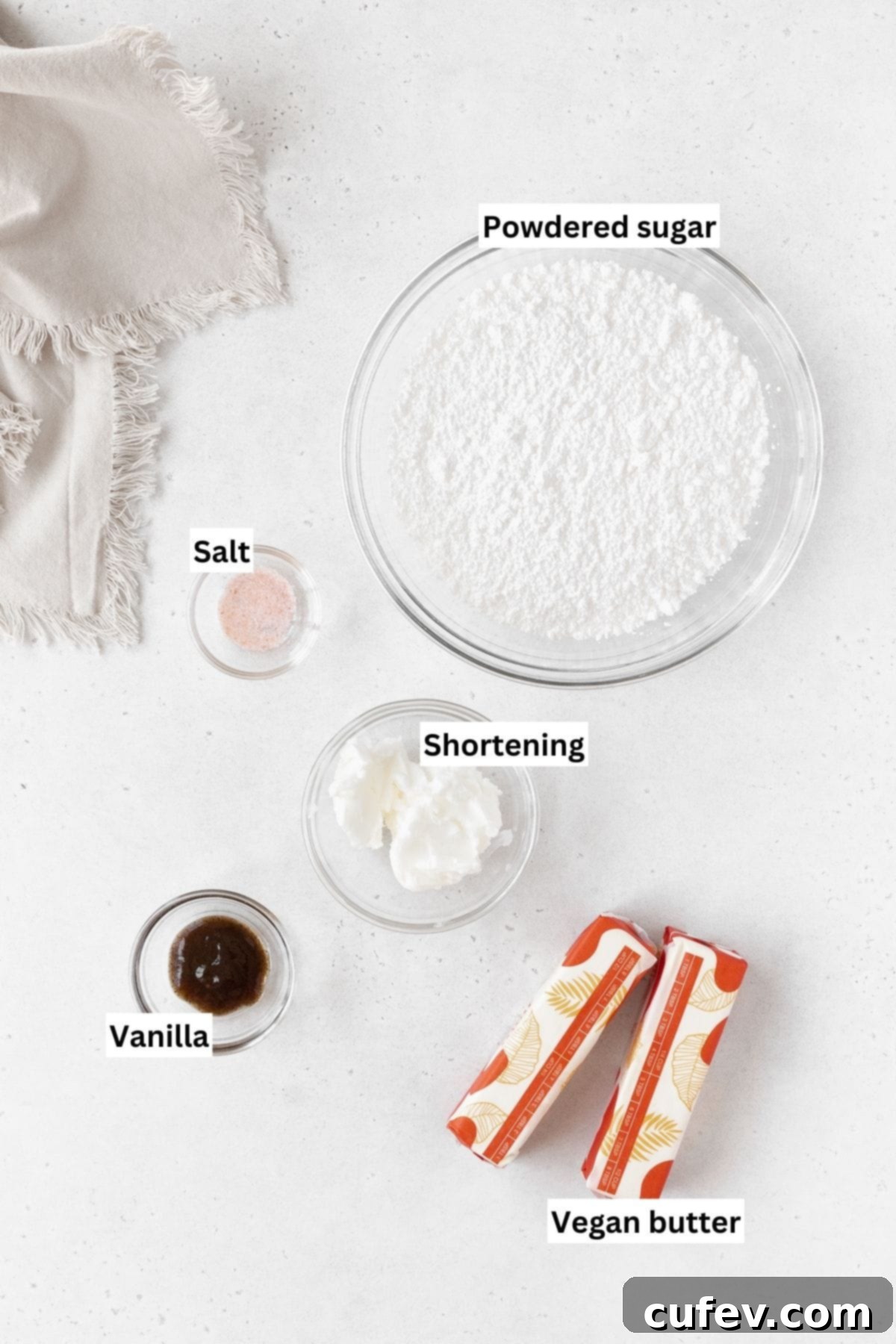 Ingredients needed to make dairy-free buttercream frosting laid out on a white table with text overlay.
