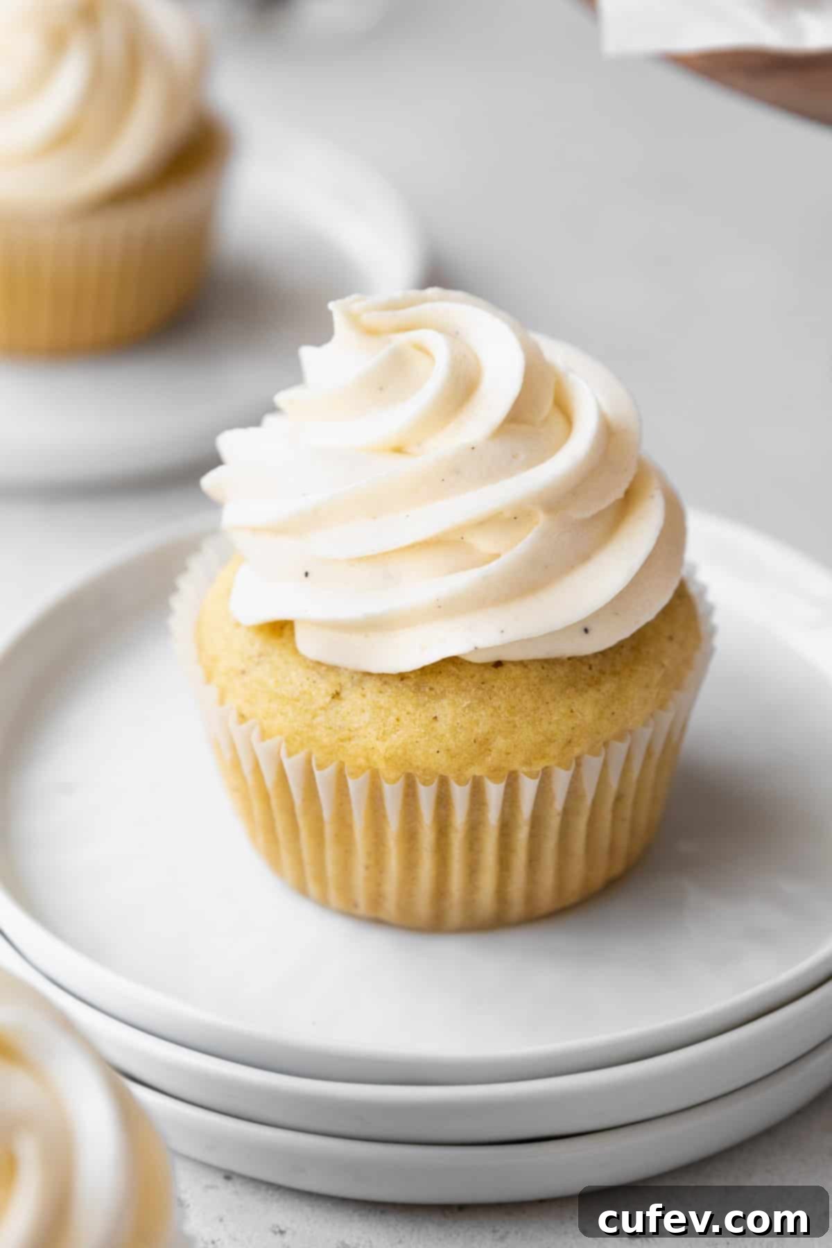45 degree angle shot of dairy-free vegan frosting piped into a high swirl on homemade vanilla bean cupcakes.
