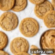 A square shot of soft and chewy dairy-free peanut butter cookies on parchment paper with a bowl of peanut butter on the side.