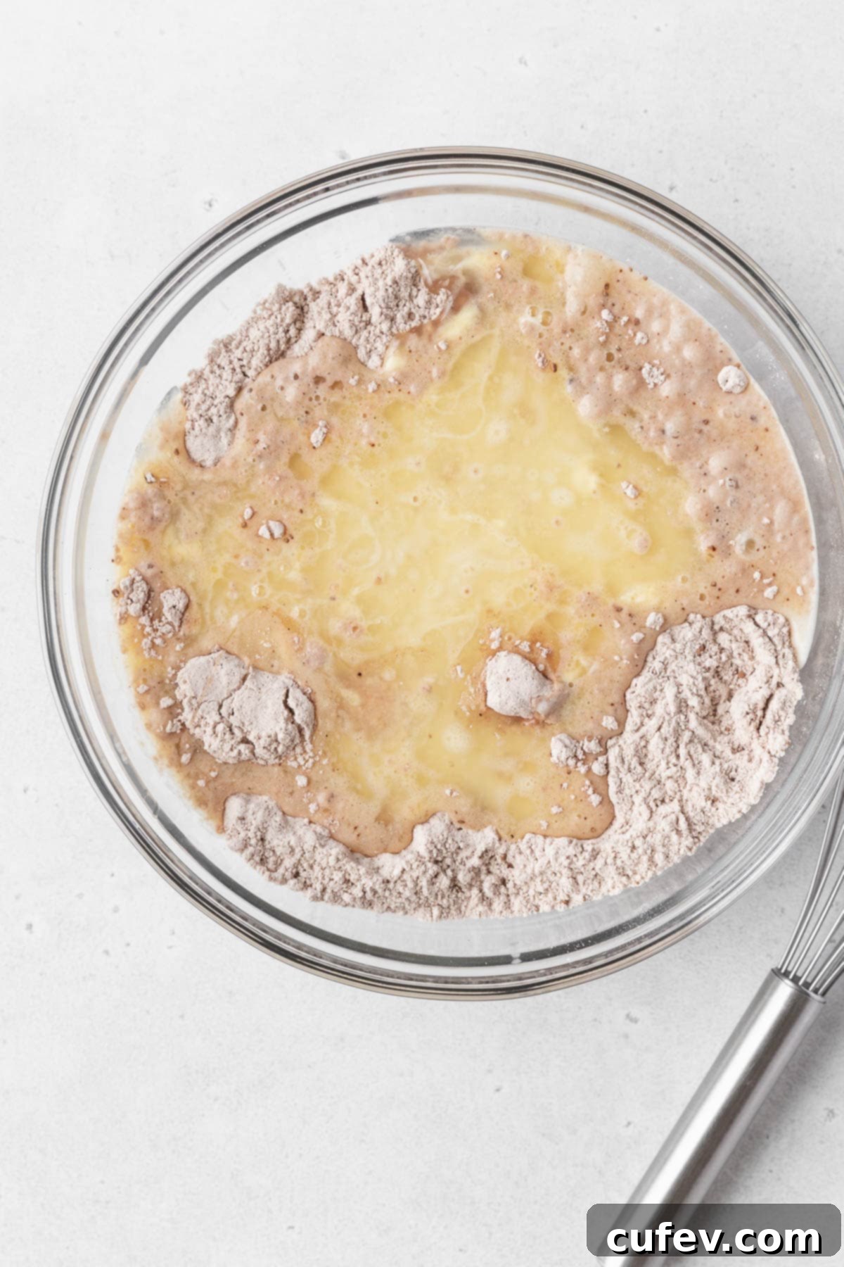 A glass mixing bowl of wet and dry waffle ingredients before mixing.