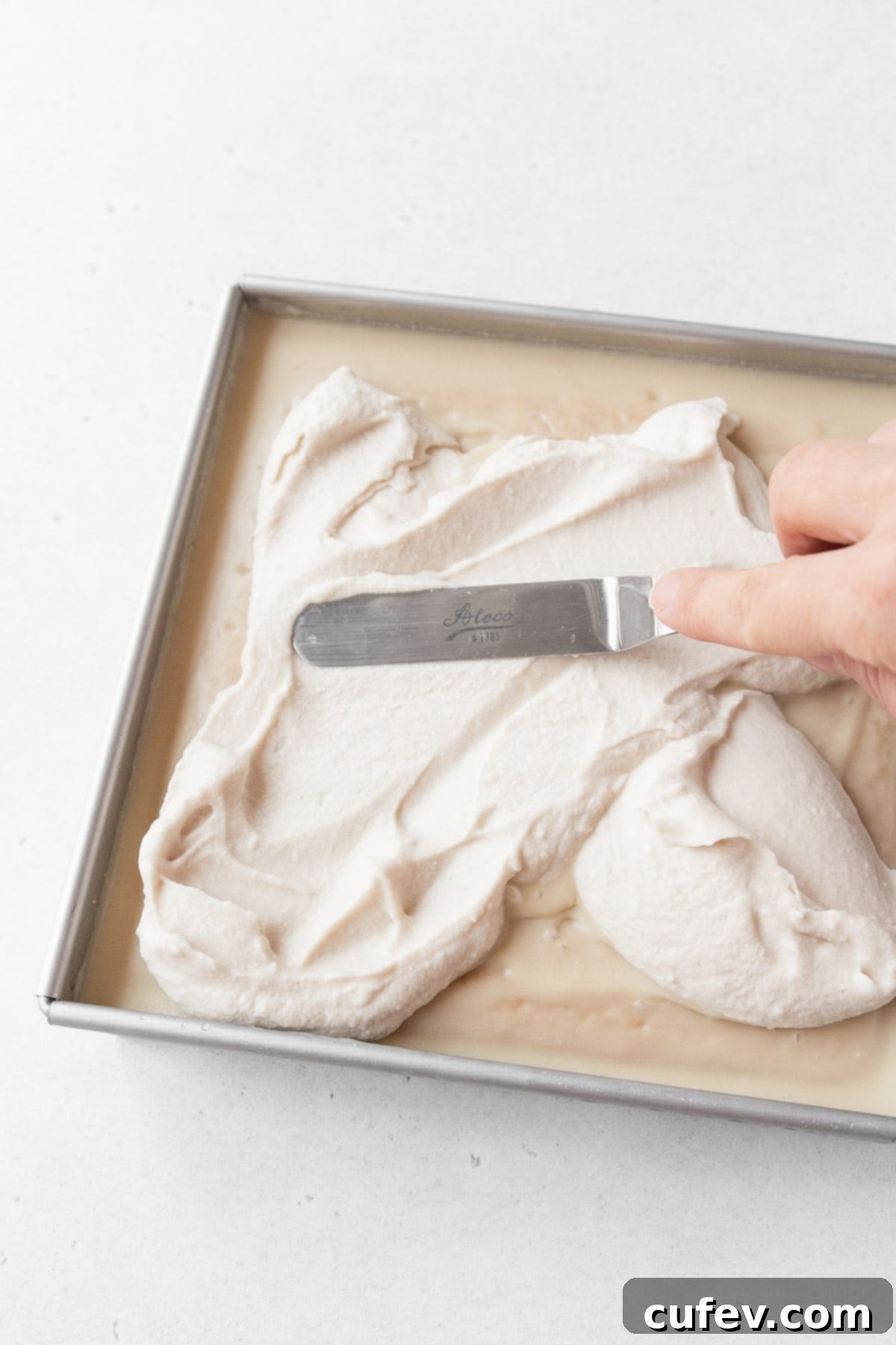 Indulgent Gluten-Free and Dairy-Free Tres Leches Cake 14 Spreading the non-dairy whipped cream on the gluten-free and dairy-free tres leches cake.