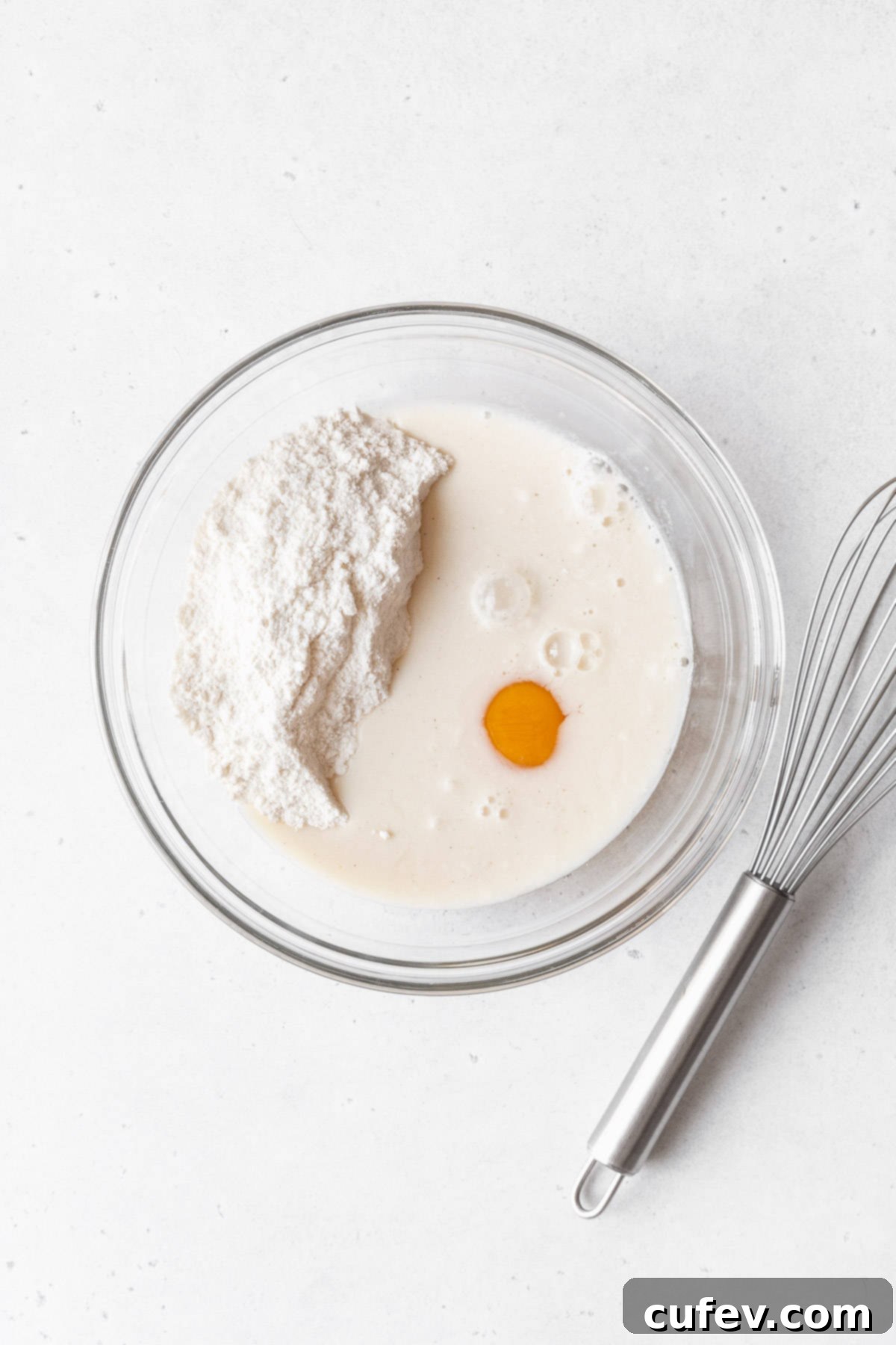 Muffin mix, egg, and milk freshly added to a mixing bowl, ready to be combined into batter.