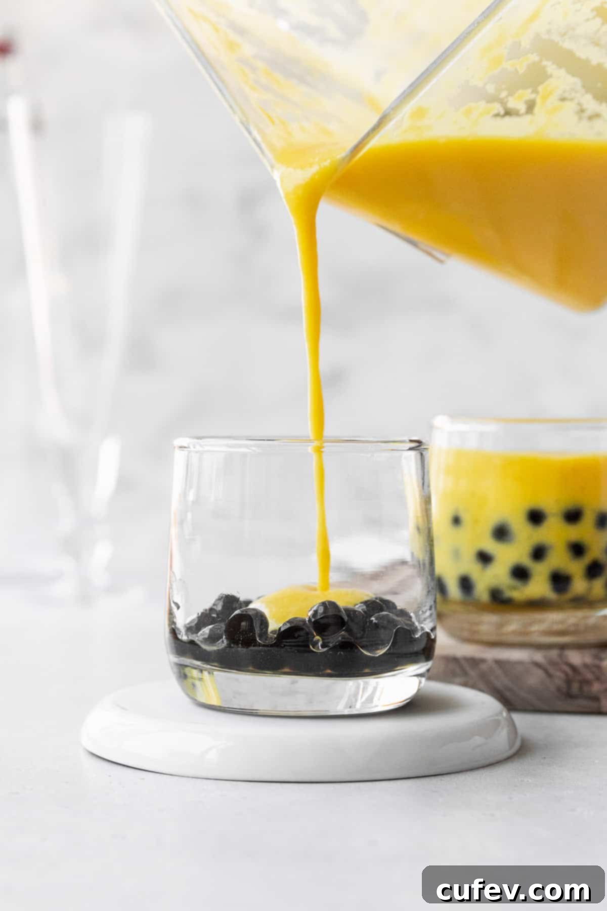Tropical Mango Bubble Tea 11 Pouring the luscious mango puree into a small glass already containing boba pearls.