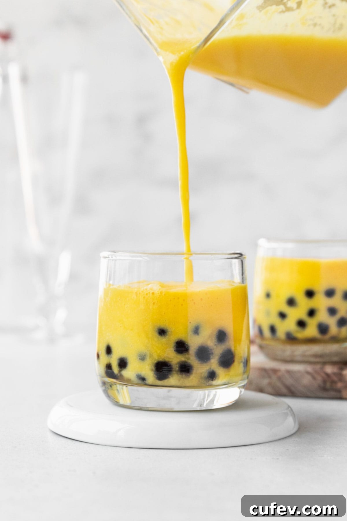 Tropical Mango Bubble Tea 12 Filling up a small glass with freshly made mango boba tea, showcasing the layers of boba and creamy drink.