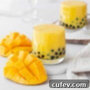 Tropical Mango Bubble Tea 15 A close-up of a glass of homemade mango boba tea with a straw, showcasing the boba pearls at the bottom.