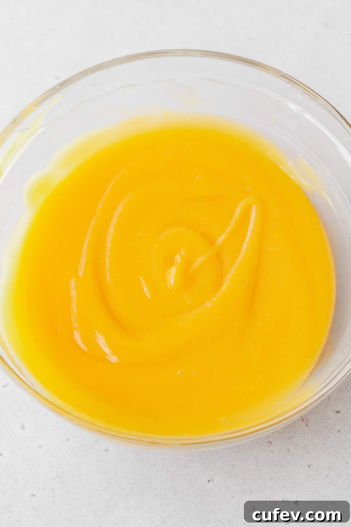 The dairy-free lemon curd filling, now smooth, glossy, and beautifully whisked in a glass mixing bowl, ready for the crust.