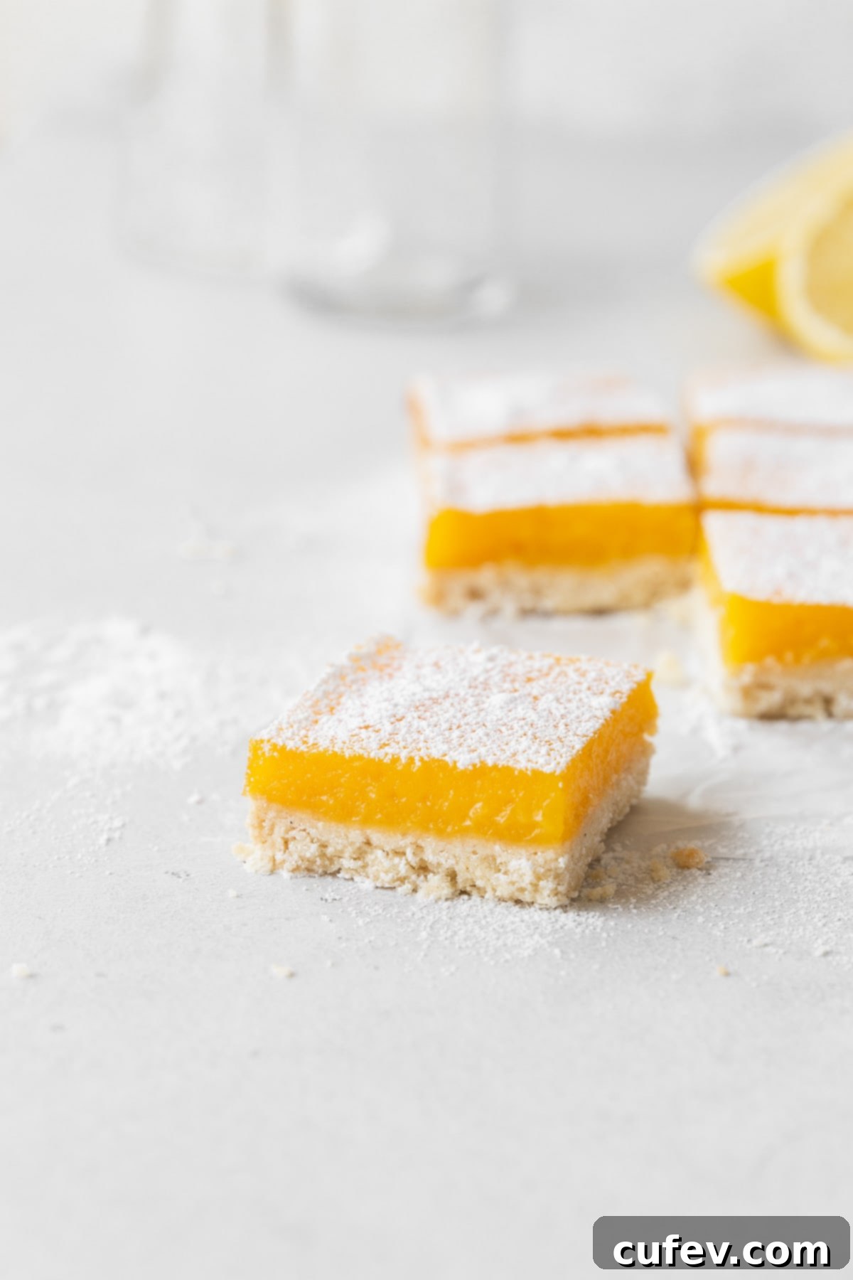 A side view of perfectly cut dairy-free lemon bars, showcasing their golden crust and vibrant lemon filling, arranged artfully on a counter.