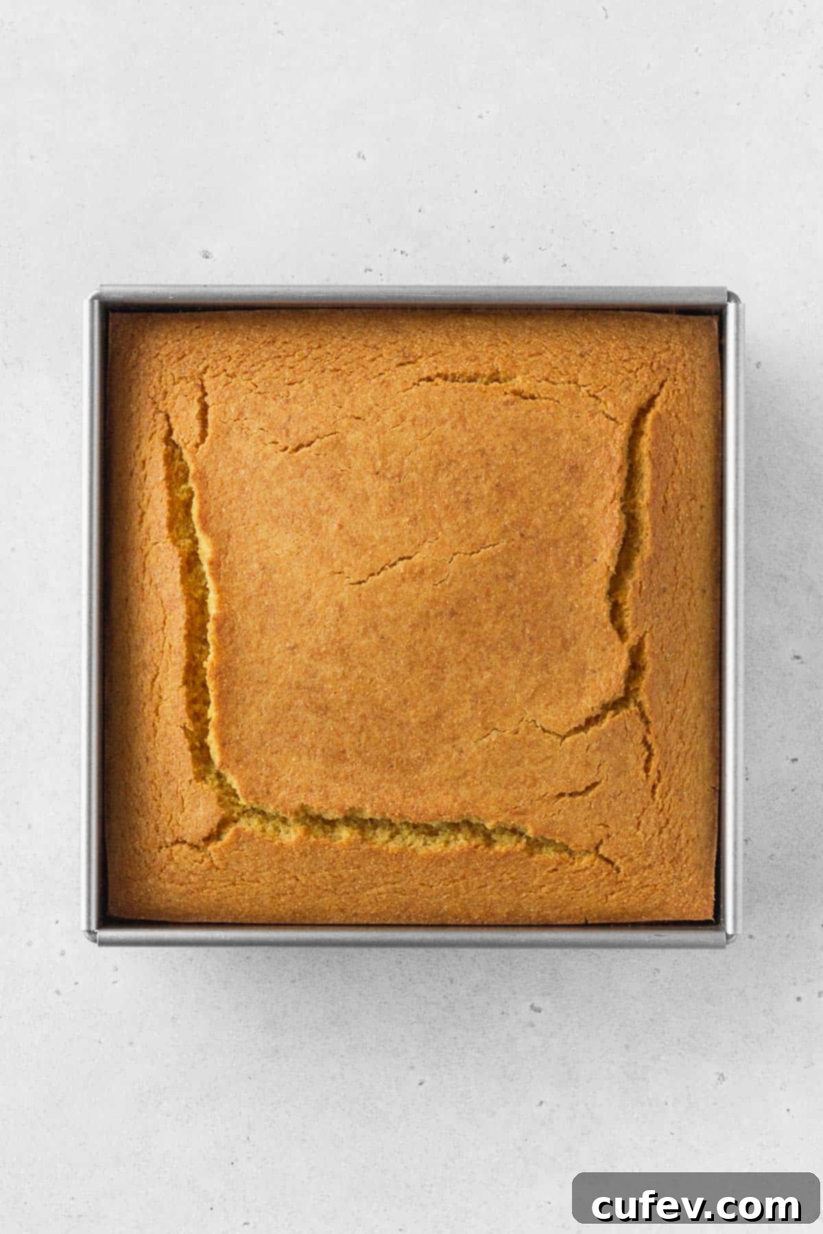 An overhead shot of a freshly baked, golden-brown pan of cornbread, showing a perfect, even bake and a slightly crackled top.