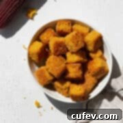 Close-up shot of a small dish of golden-brown cornbread croutons, highlighting their crispy texture and delicious appearance.