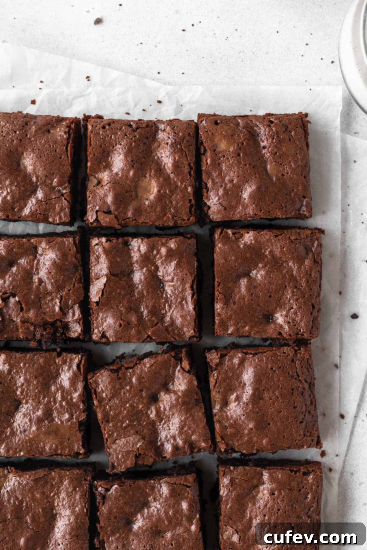 An overhead shot of a pan of sliced brownies on parchment paper.