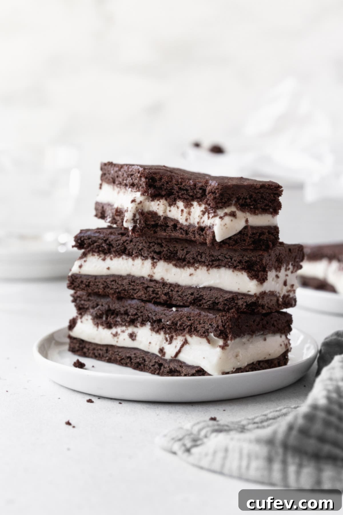 A stack of ice cream sandwich cookies on a small white dish with a large bite taken out of one of the cookies.